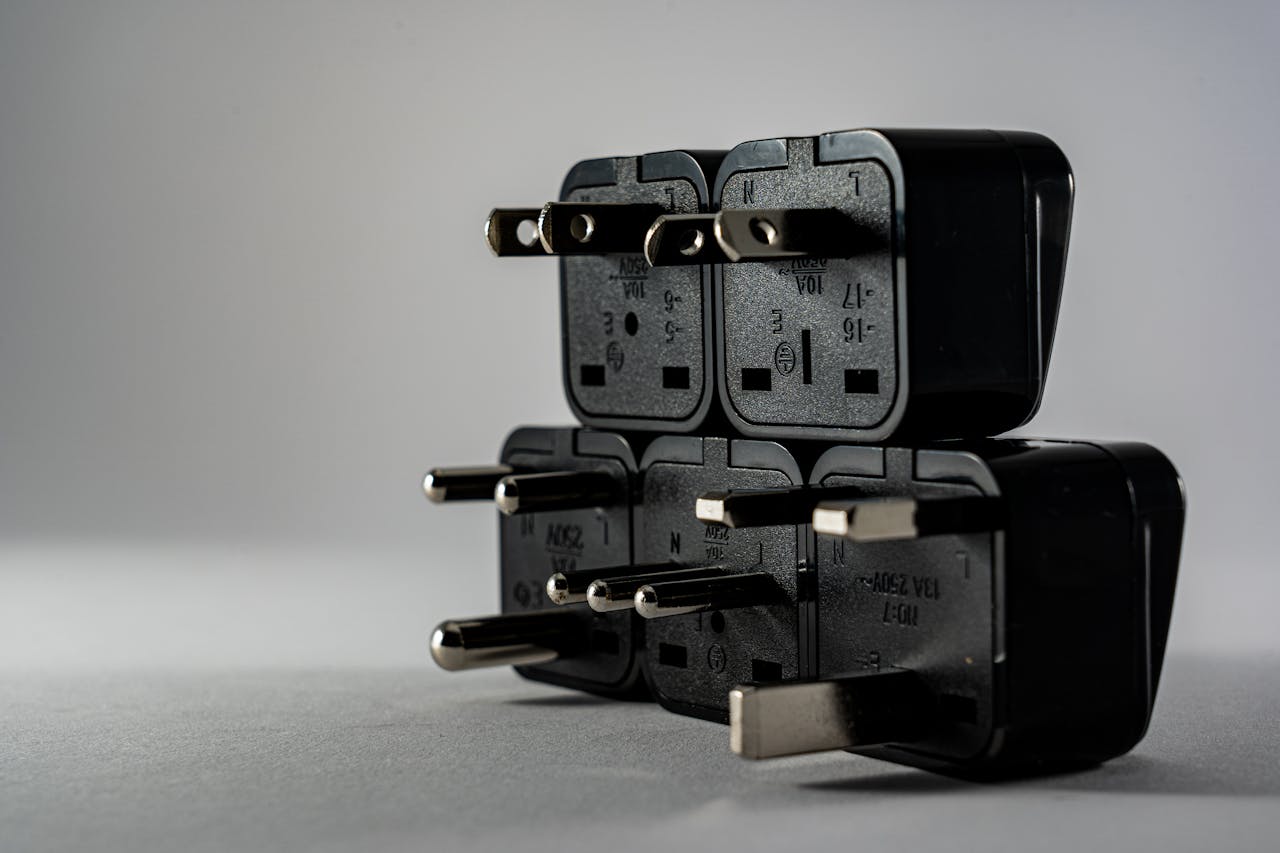 Services-01 Close-up of black electrical adapters stacked on a gray background.